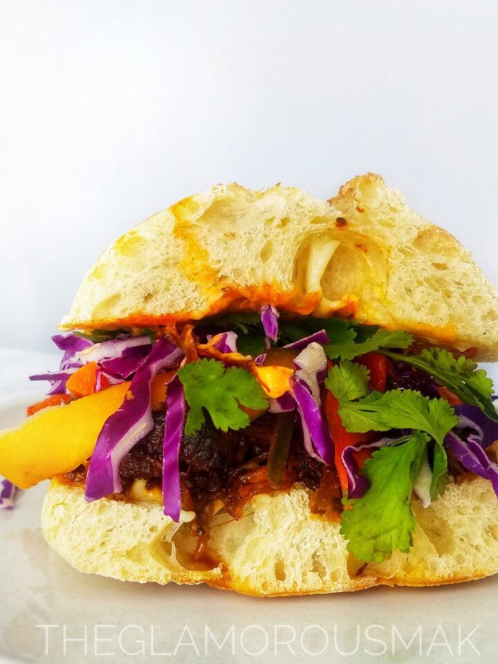 banh mi sandwich with pickled vegetables, cilantro and red cabbage. These easy banh mi pulled pork sandwich recipe is vietnamese street food made right in your crockpot slow cooker. topped with quick pickled vegetables perfect for meal planning, meal prep, lunch, dinner, meal ideas. Easy marinade, healthy.