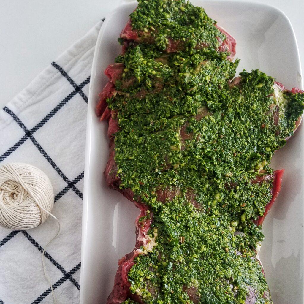 mandyolive.com boneless leg of lamb recipe topped with pesto.