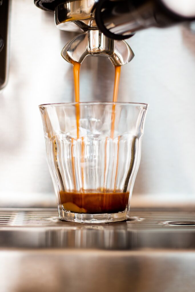 pulling espresso into a small glass depicted on post about espresso grind settings. 