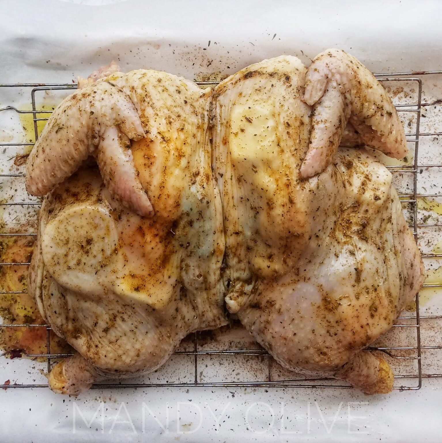 This picture shows a spatchcock chicken stuffed with lemon and butter. This spatchcock chicken recipe is a quick, simple and easy way to make moist juicy chicken with crispy chicken skin. How to roast a whole chicken in the oven on a sheet pan for dinner, meal prep with butterflied chicken. What to do with a whole chicken? How to bake a whole chicken for dinner idea and meal prepping.