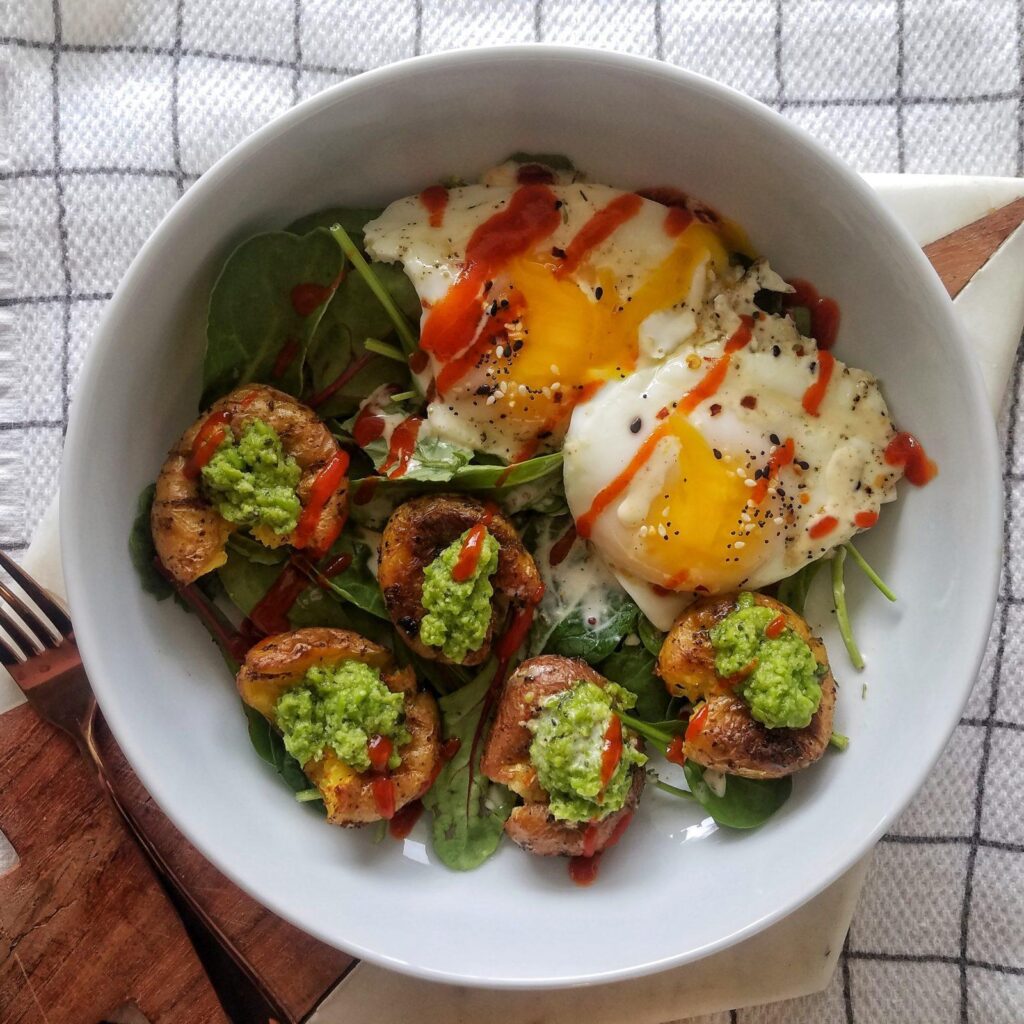quick and easy breakfast salad made with roasted baby potatoes, pea pesto and fried eggs topped with a creamy dressing and sriracha | potatoes and eggs, pesto recipes, breakfast ideas, brunch recipes, smashed potatoes, crispy, healthy, weight loss, 30 minute meals, fingerling potatoes, eggs with hot sauce, recipes with pesto