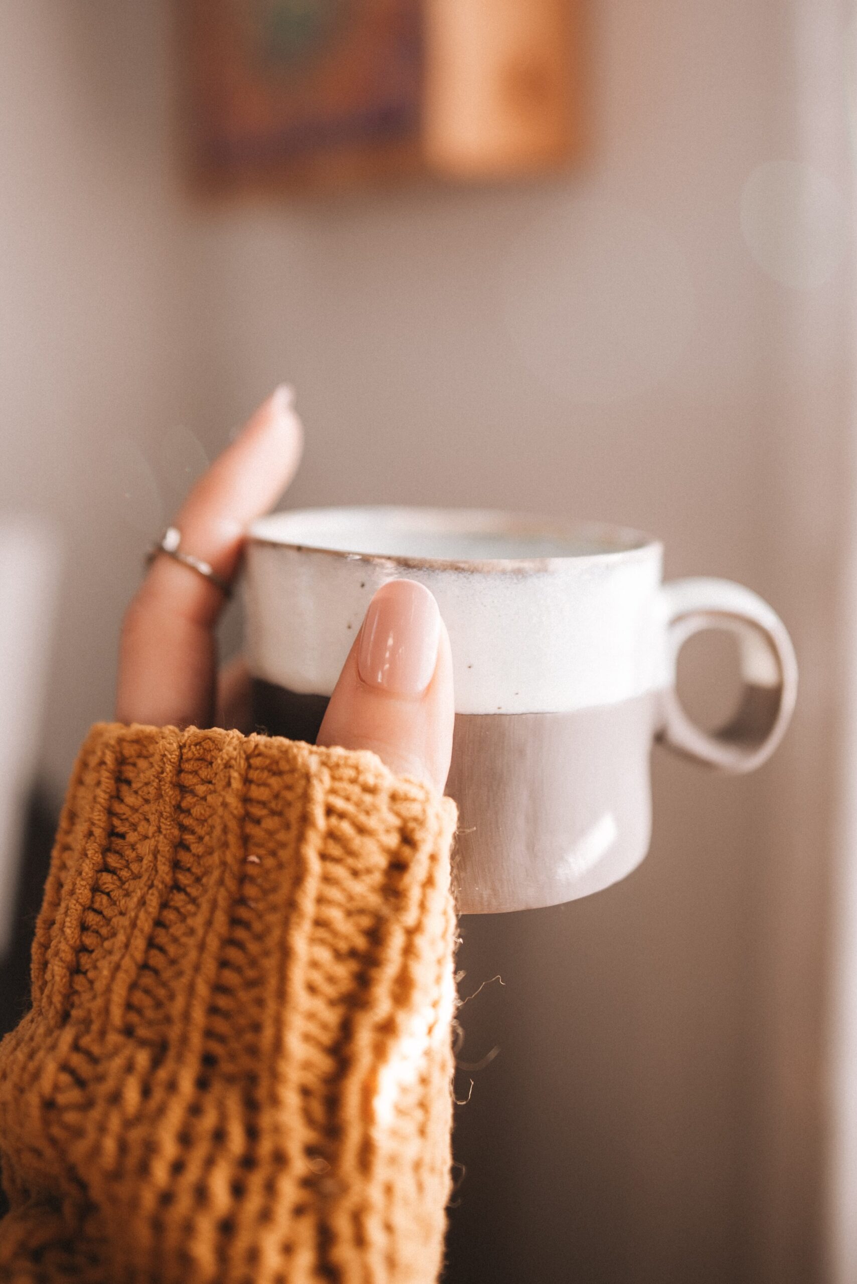 Starbucks copycat apple crisp macchiato recipe. woman with chunky sweater holding a white and grey mug.