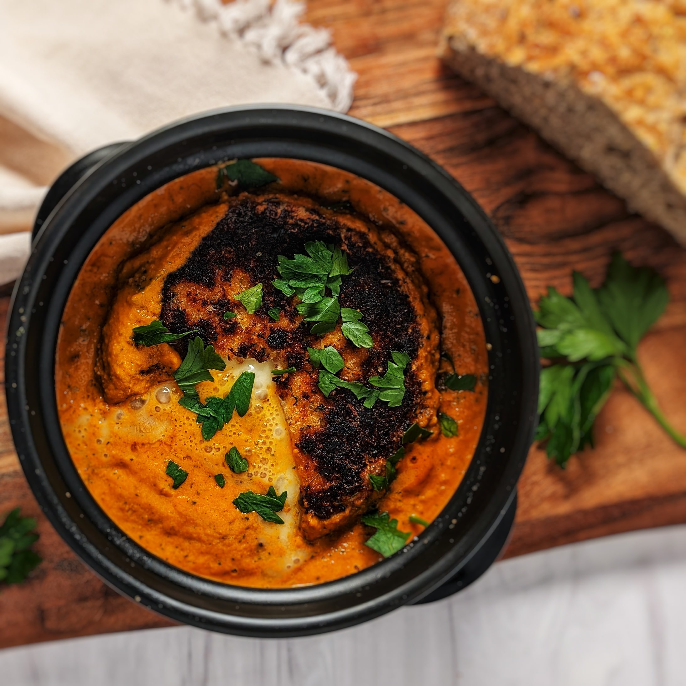 pan fried brie in romesco in dolsot stone bowl with bread on top of wooden board