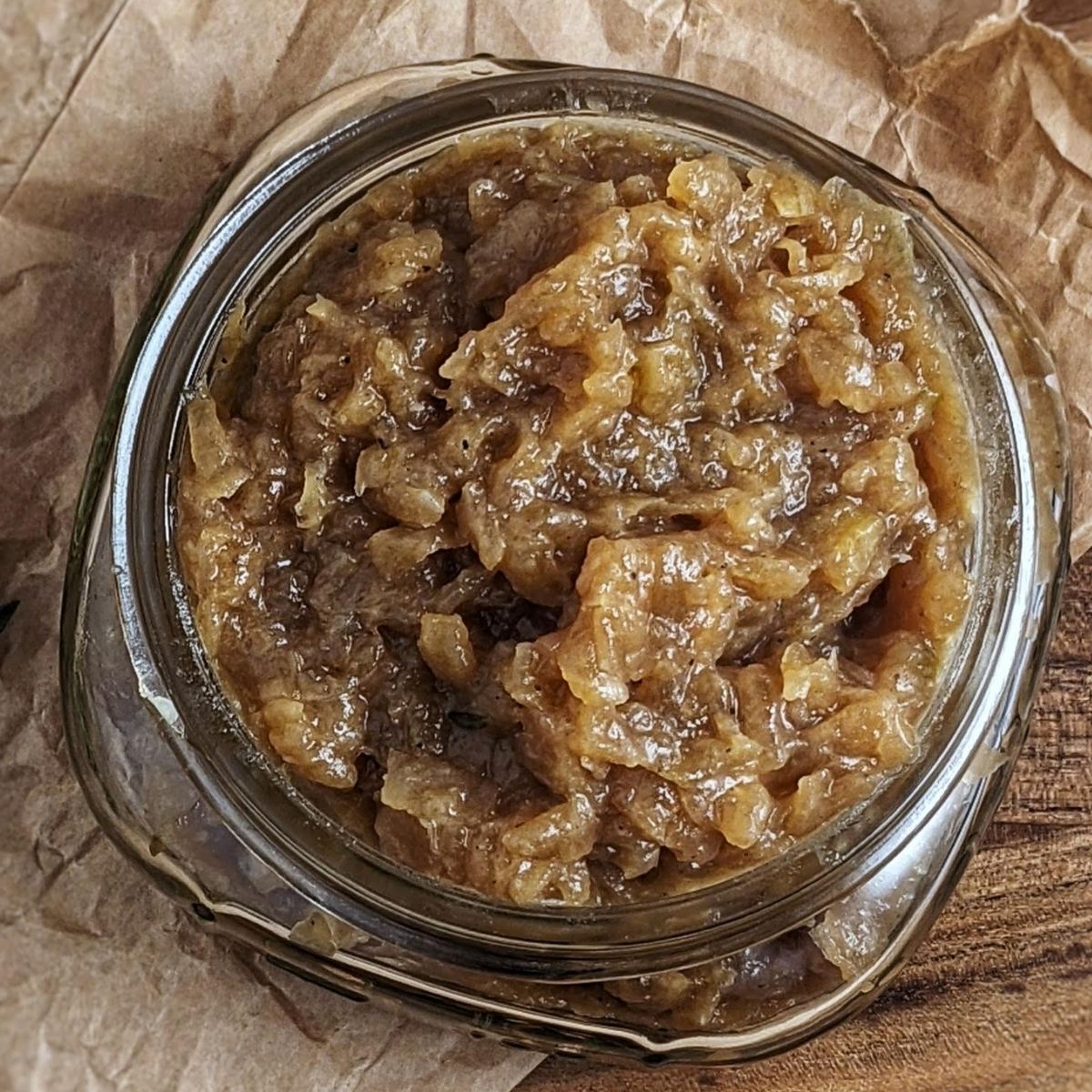 apple cider onion jam in small mason jar on top brown paper background