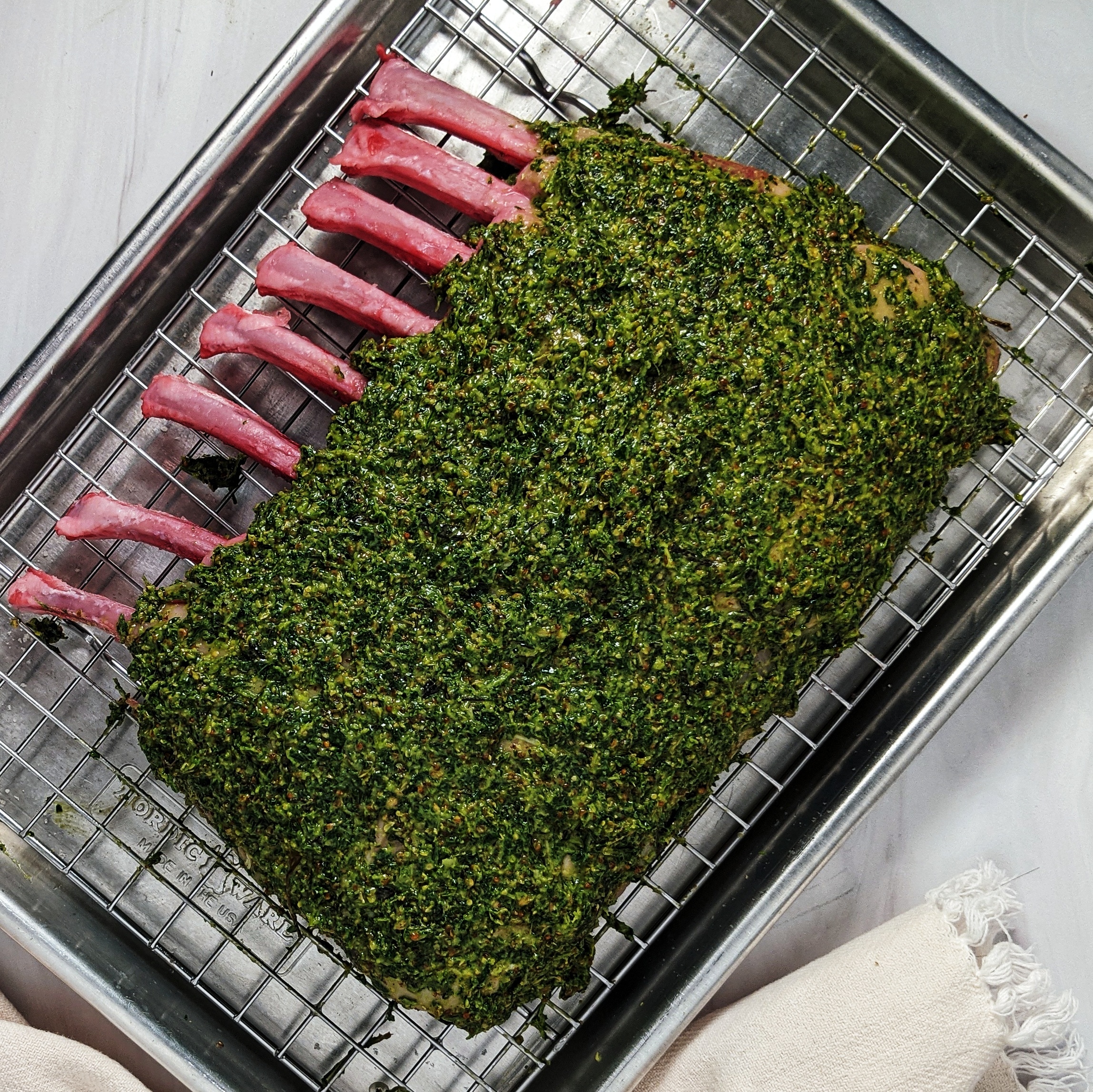 herb rub covering lamb on baking sheet