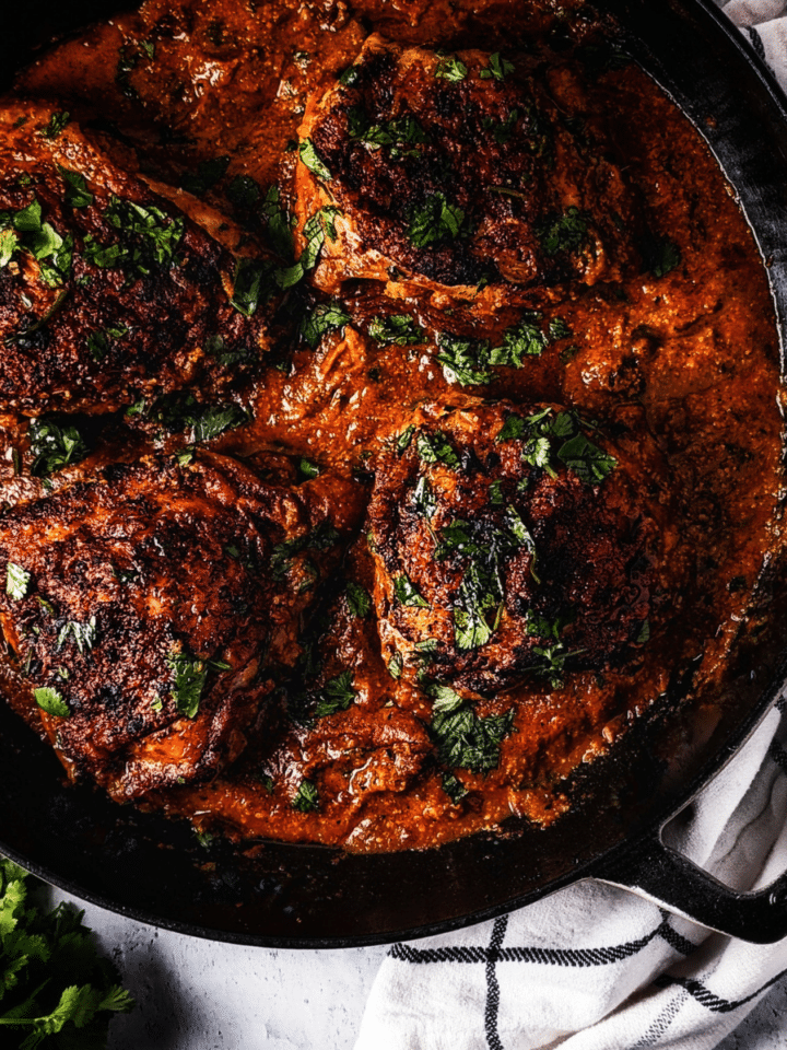 pepita mole chicken thighs in an enamel cast iron pan with cilantro