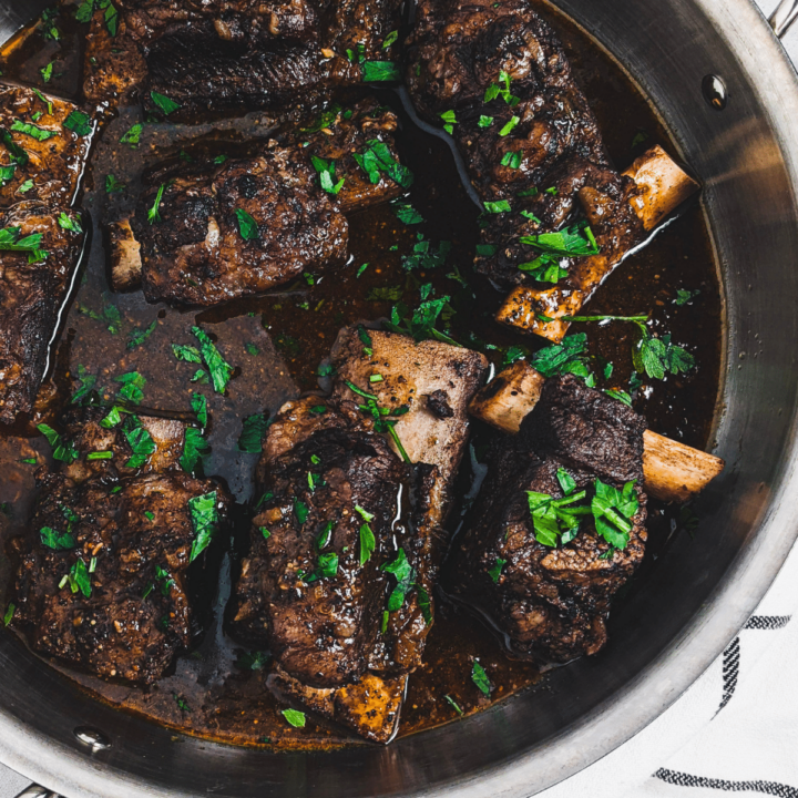 coffee rubbed short ribs in stainless steel pan garnished with parsley