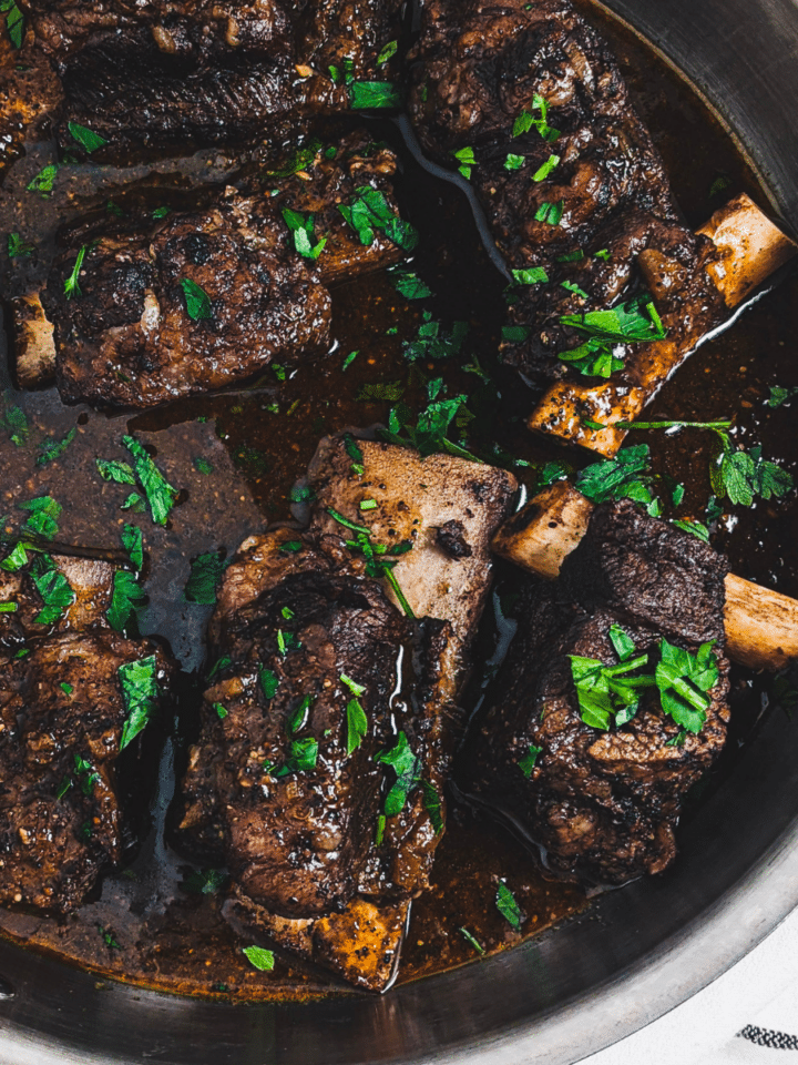 coffee rubbed short ribs in stainless steel pan garnished with parsley