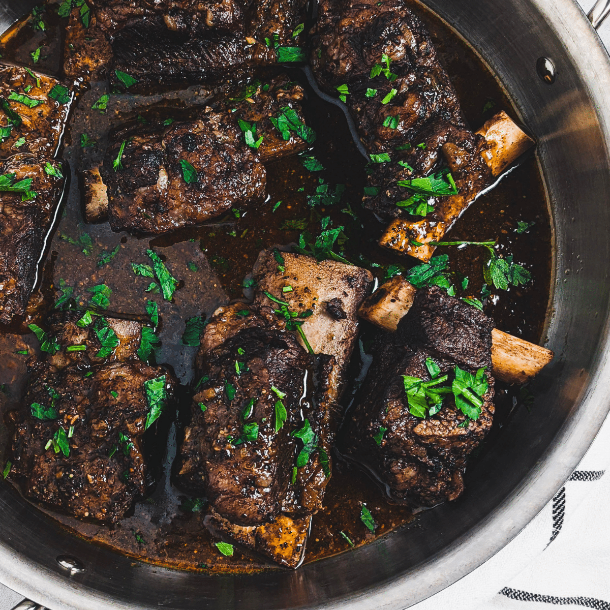 coffee rubbed short ribs recipe sprinkled with parsley in stainless steel pan.