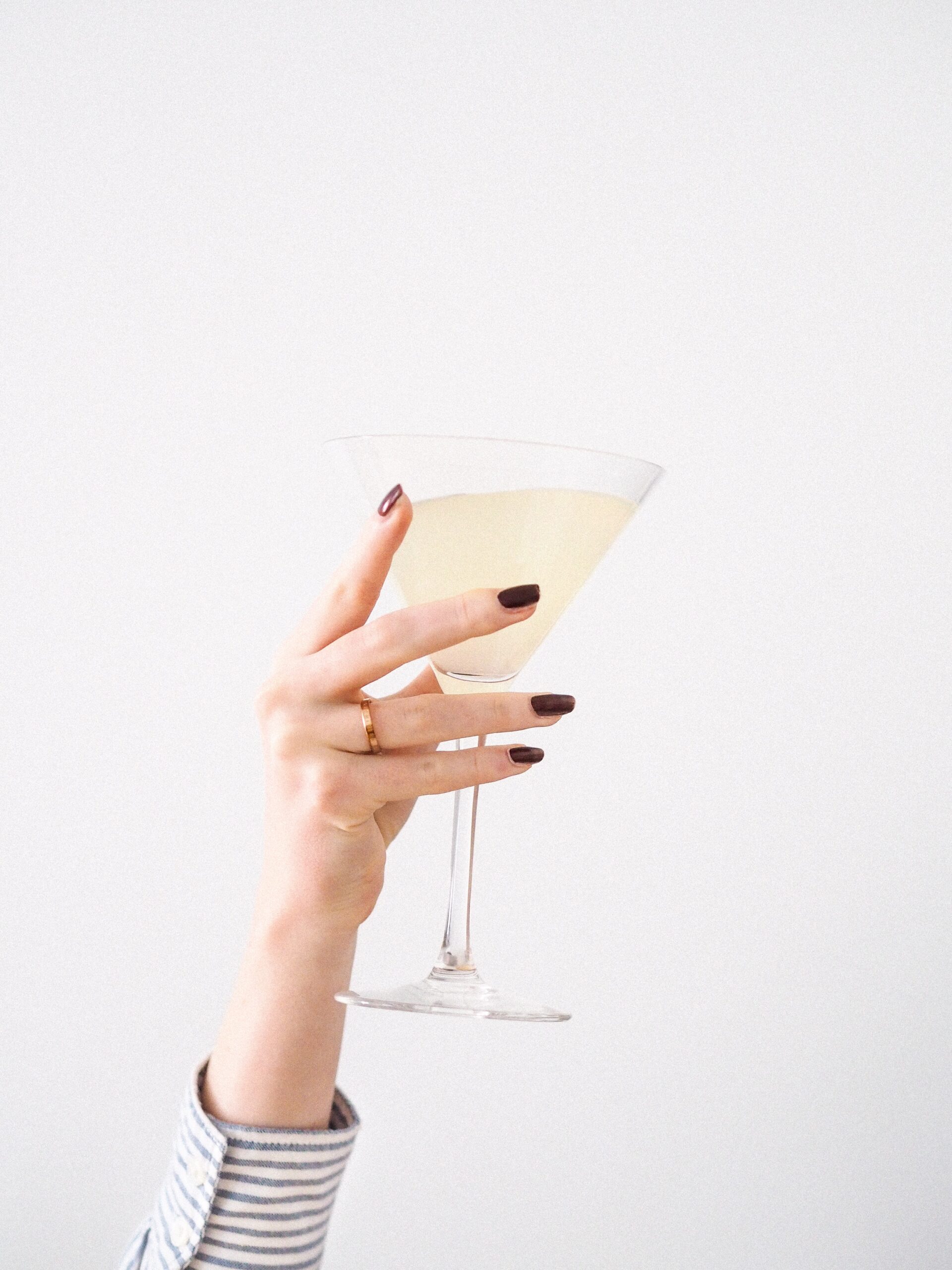 lemon champagne cocktail held in hand with red nail polish